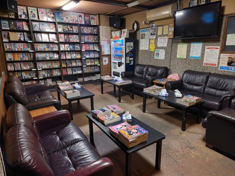 薄暗い部屋に茶色の革張りのソファとテーブルが床に点在している。