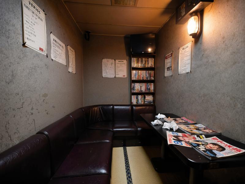 薄暗く、居心地の良い雰囲気のお部屋で、コーナーブースと新聞を敷いたテーブルが特徴です。