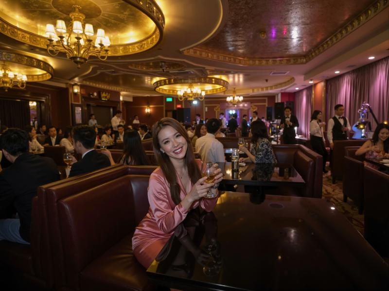 高級レストランのテーブルに座り、笑顔でワイングラスを持っている若い女性を正面から写実...。