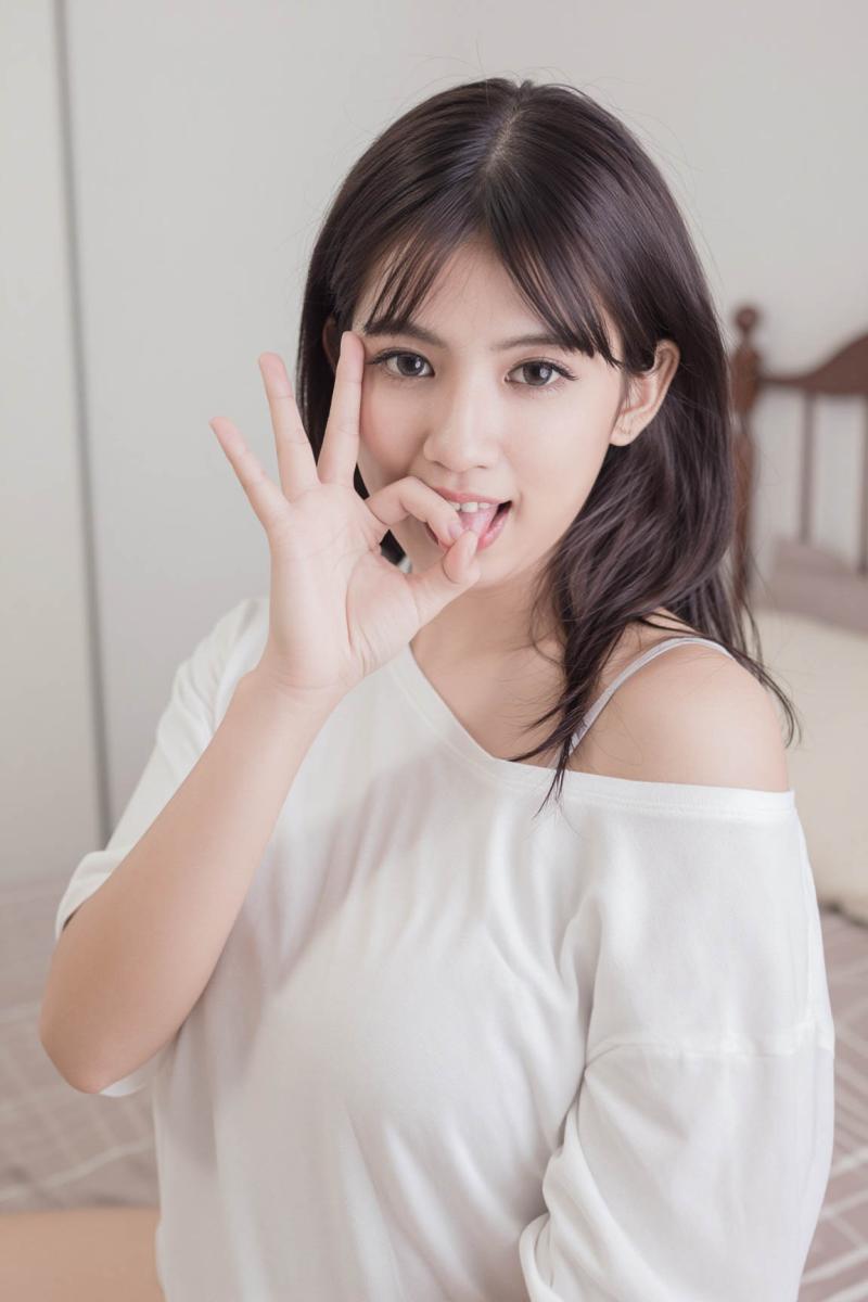 カメラに向かって微笑みながら右手でピースサインをする若い女性を正面カメラのアングルか...。